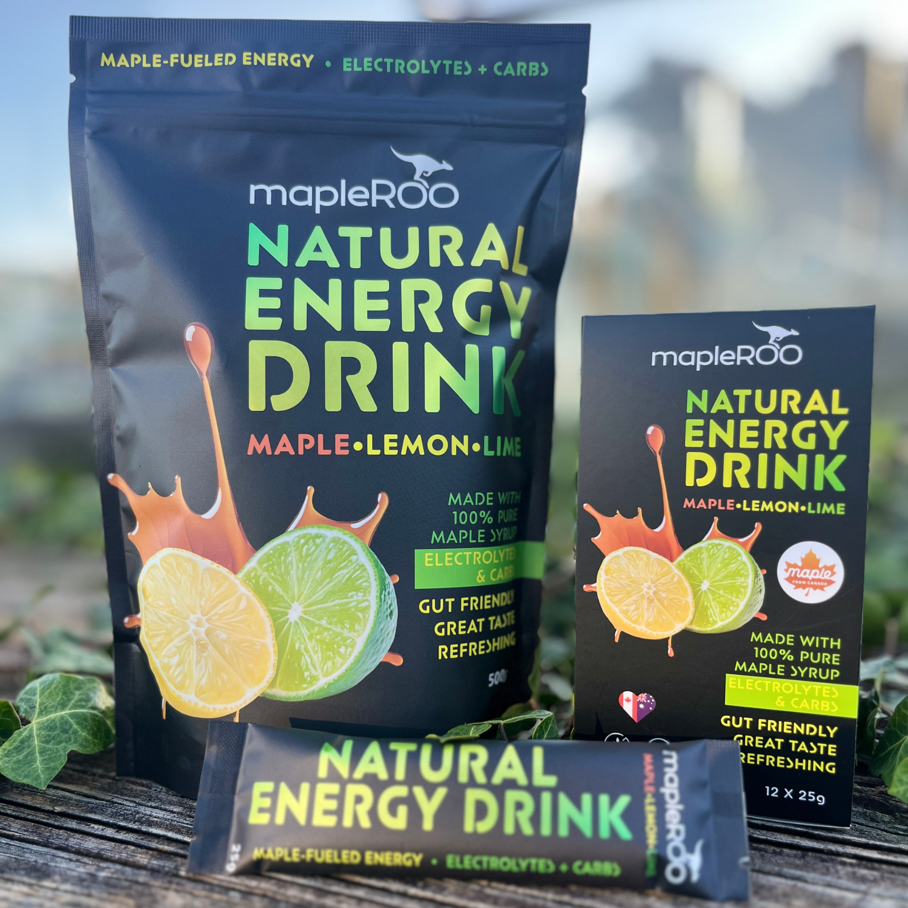 MapleROO natural energy drink packages on a wooden surface with a blurred outdoor background