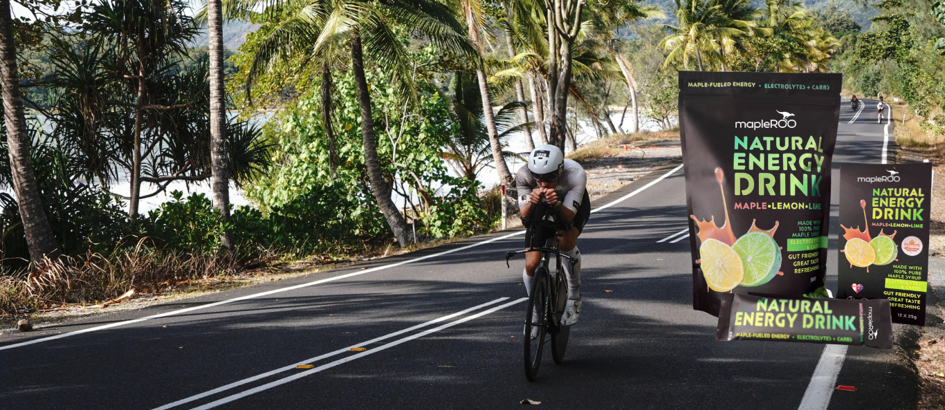 Person riding a bike on a road with mapleROO energy drink (maple Sugar) packaging in the foreground.